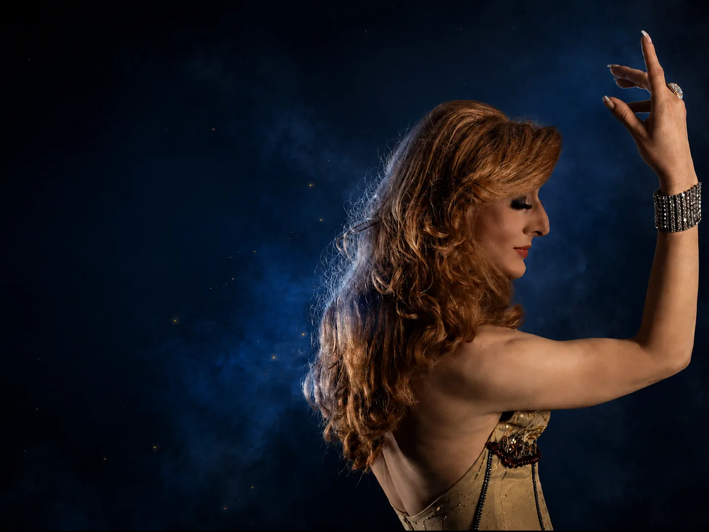 Spectacle Cabaret et Transformiste par Lady Maxx, robe dorée et pose élégante fond bleu nuit