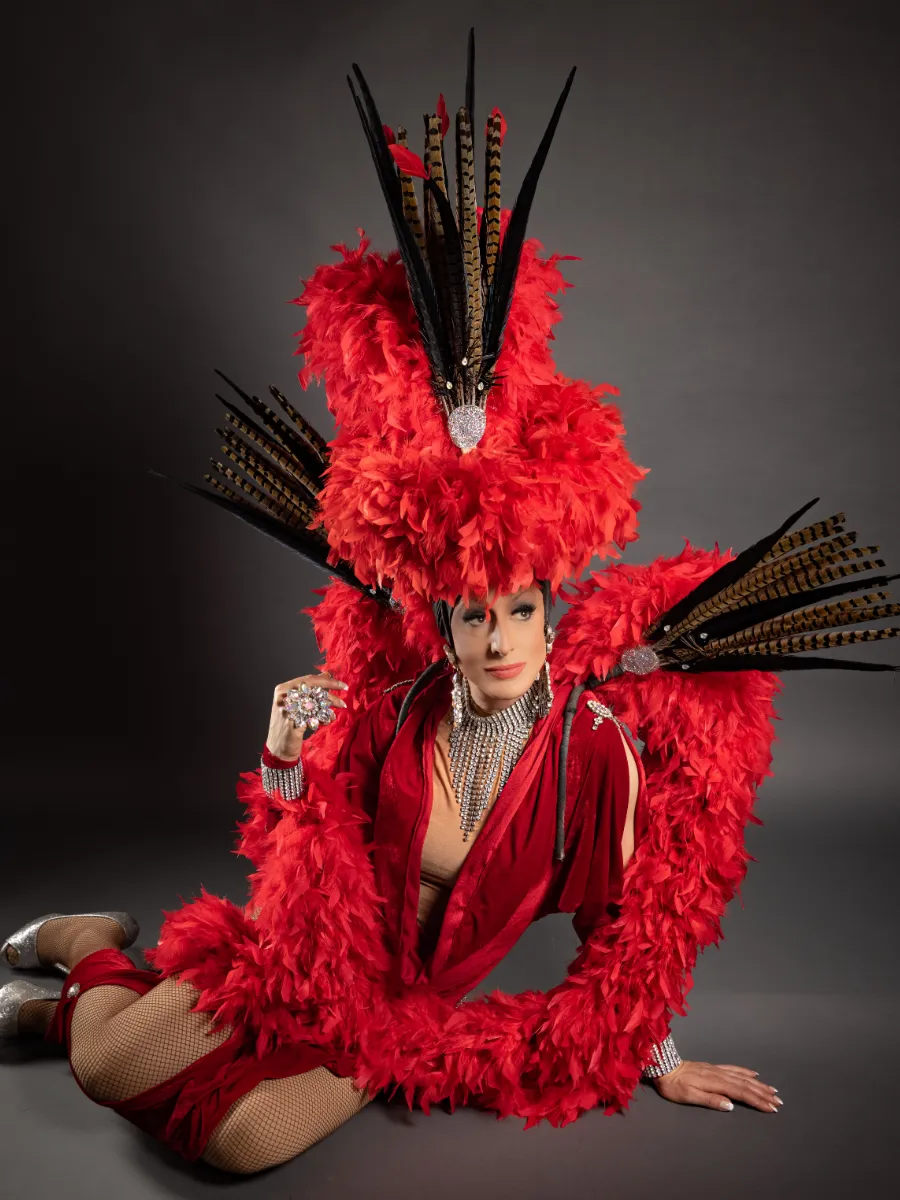 Lady Maxx en costume de plumes rouges et faisan, revue du spectacle cabaret transformiste à Paris